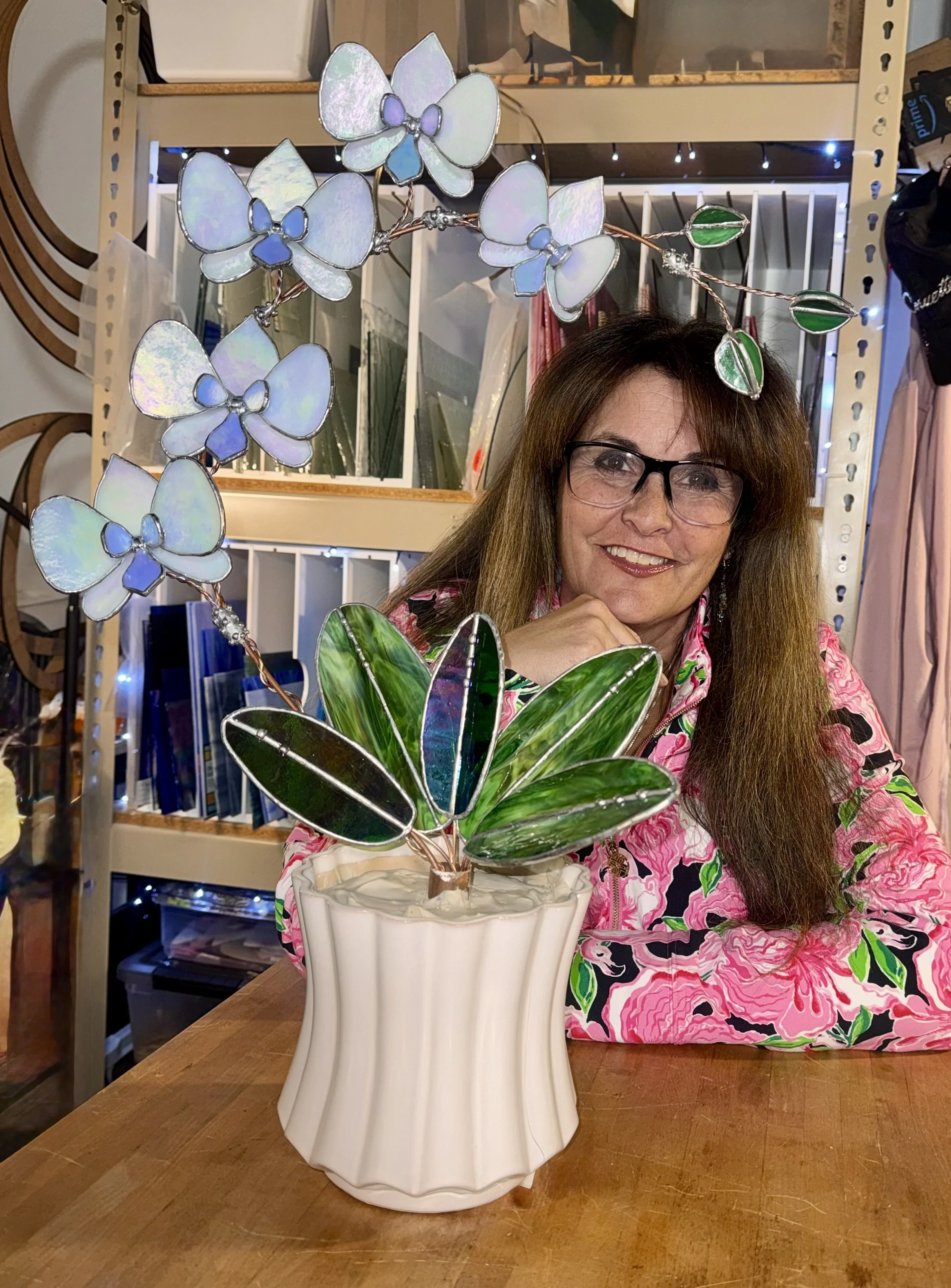 Shelli Rae Scott,  pictured in her studio with a iridescent stained glass 3D Orchid with glass leaves