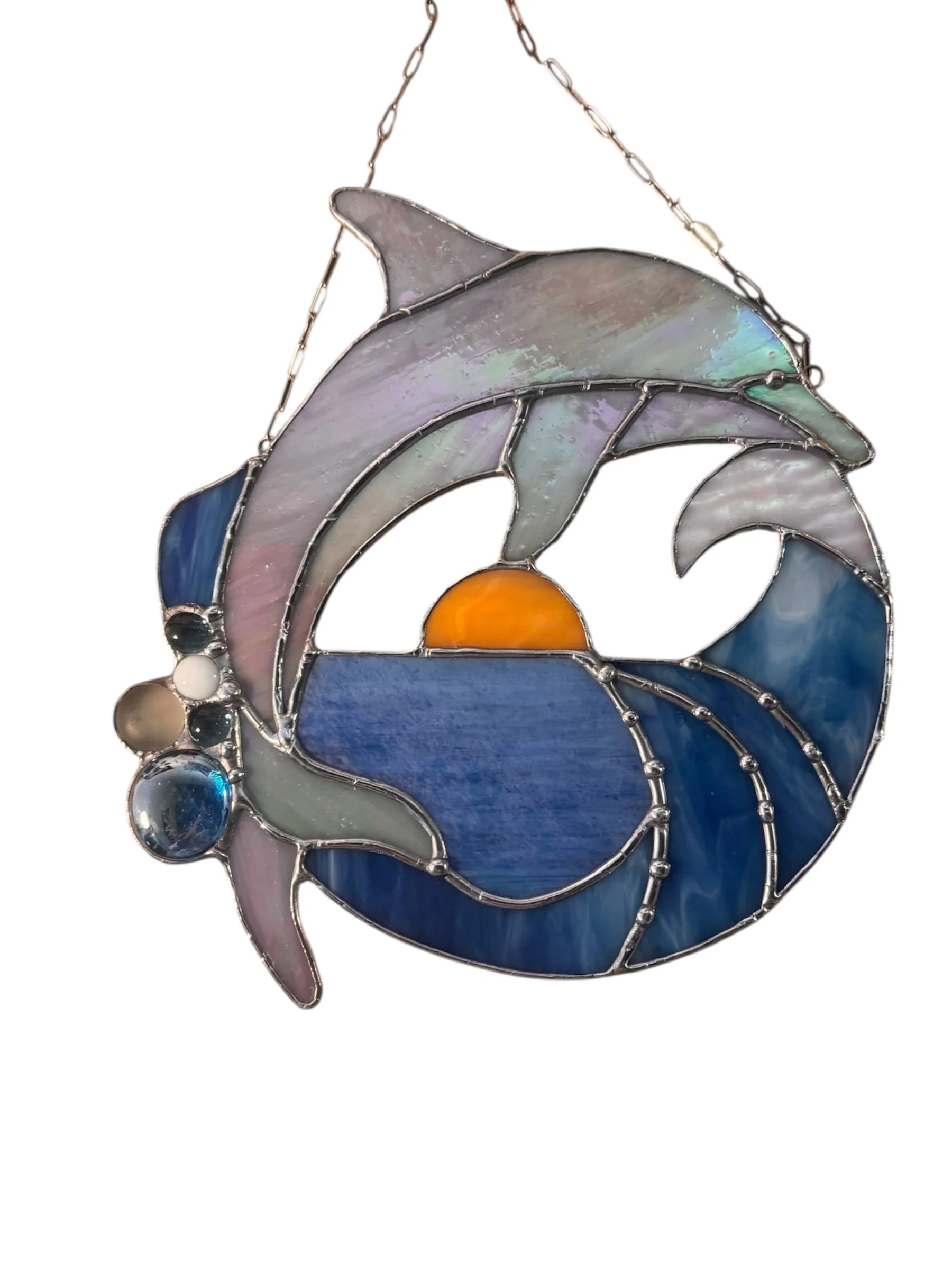 Stained glass artwork featuring dolphin jumping around a sunset over the ocean.