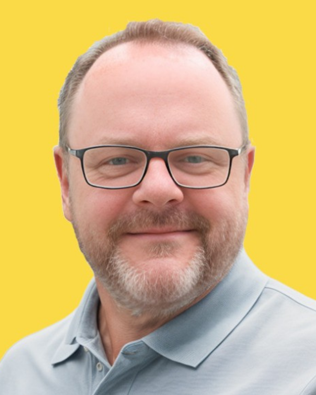 Portrait of Scott - Close-up portrait of a smiling man with glasses, beard, and mustache, wearing a light gray shirt against a bright yellow background.