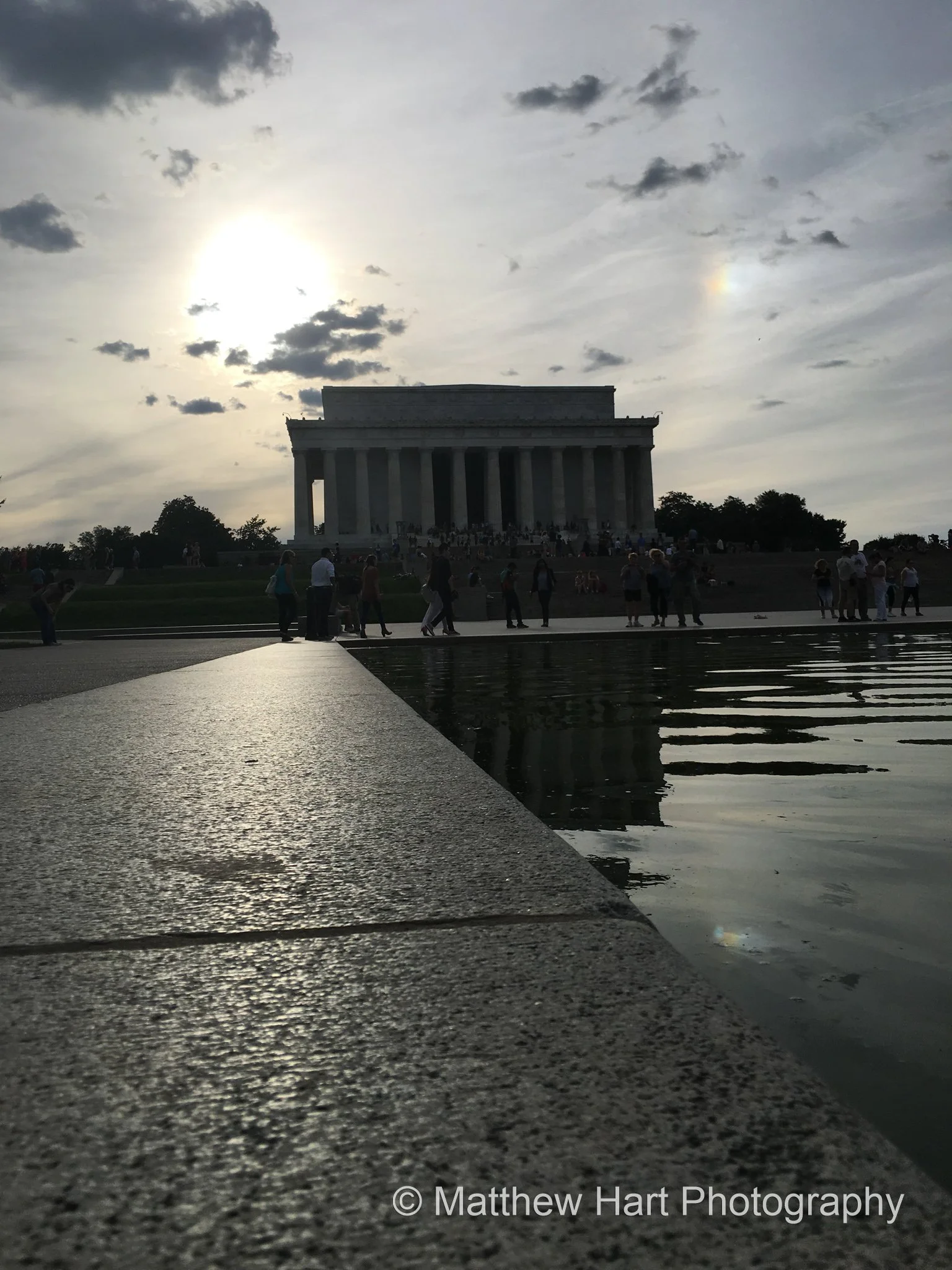 Fine art photograph of the Lincoln Memorial reflected in the Reflecting Pool, with a granite edge leading in and a sundog beside the sun.