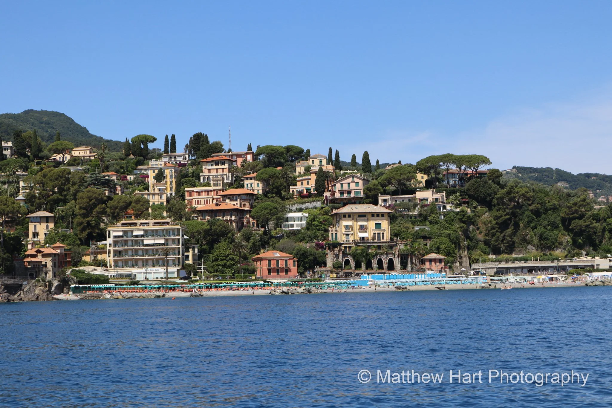 Fine art photograph of villas among pine trees on a green hillside above the sea on the Italian Riviera.