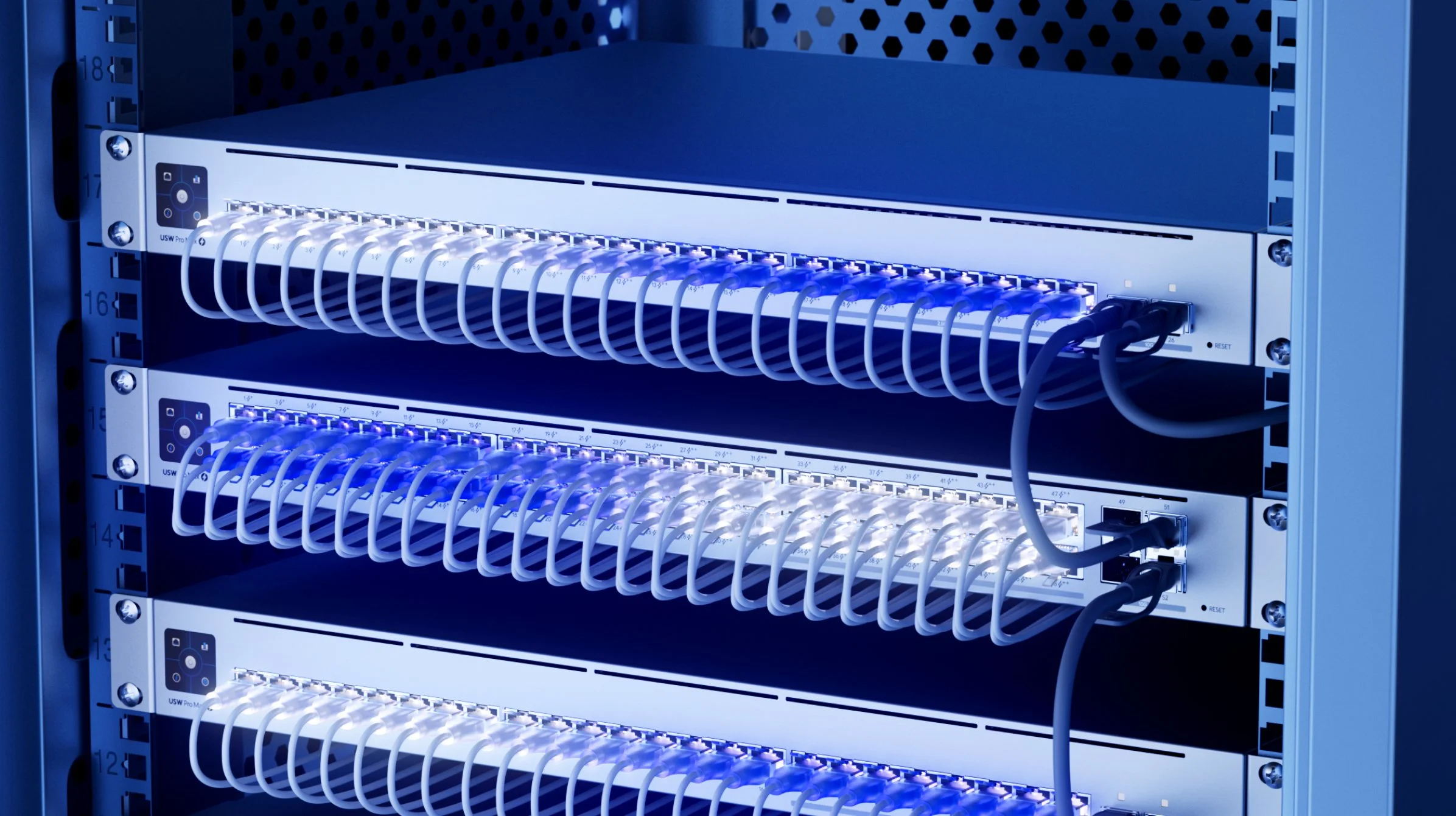 Close-up of a server rack with network switches and connected Ethernet cables, illuminated with blue lighting.