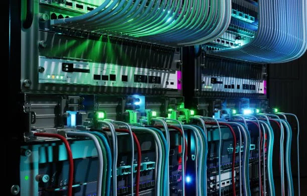 Server racks with network cables and equipment in a data center, illuminated by colorful LED lights.