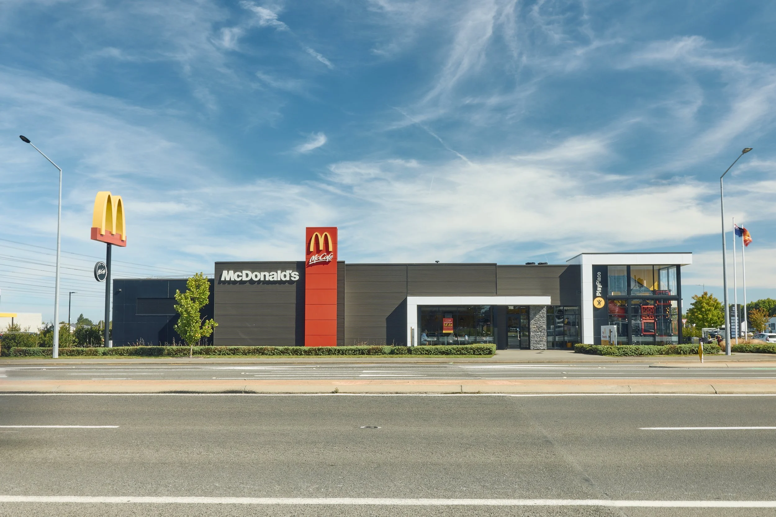 Exterior view of a McDonald's restaurant with a clear blue sky, magnified golden arches logo, and modern building design.