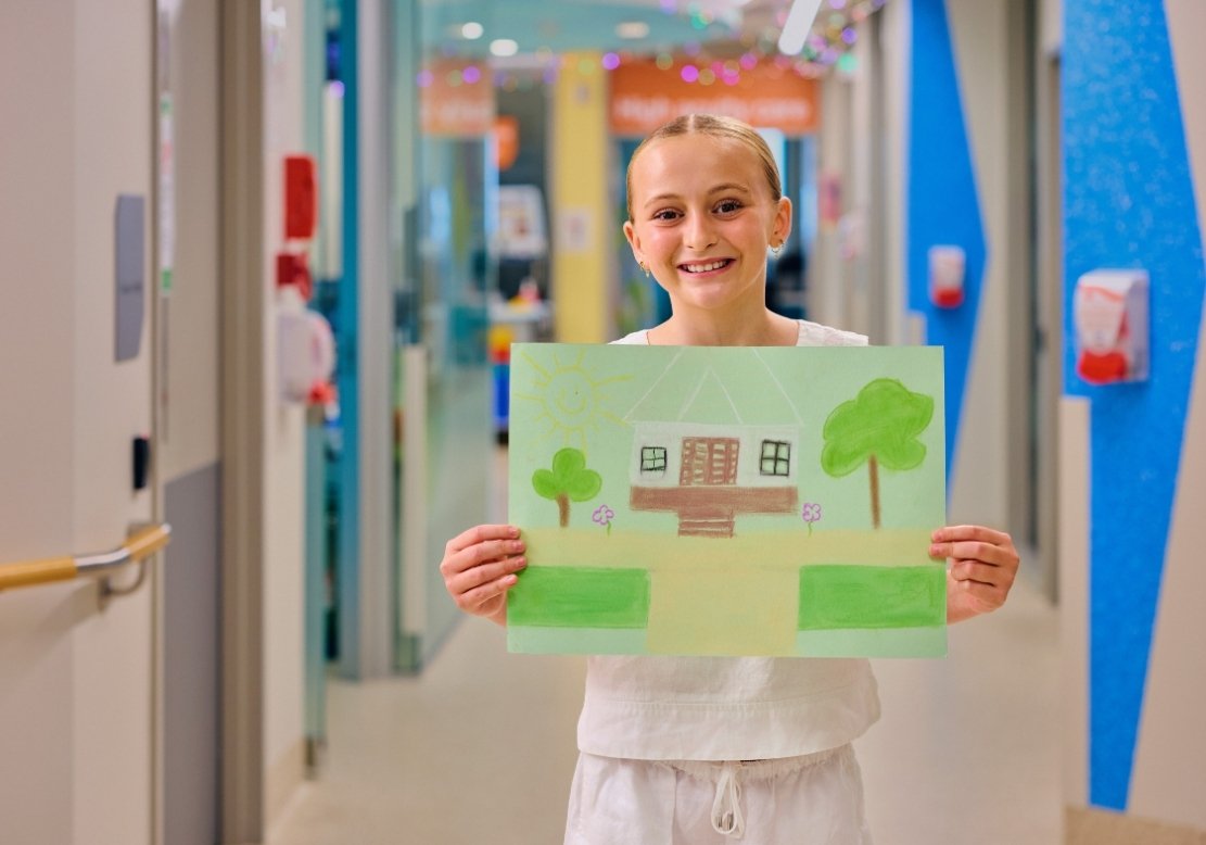 Girl in hospital holding up drawing
