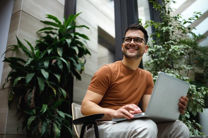 Man working on computer in green office, representing B Corps in the For-Purpose Sector