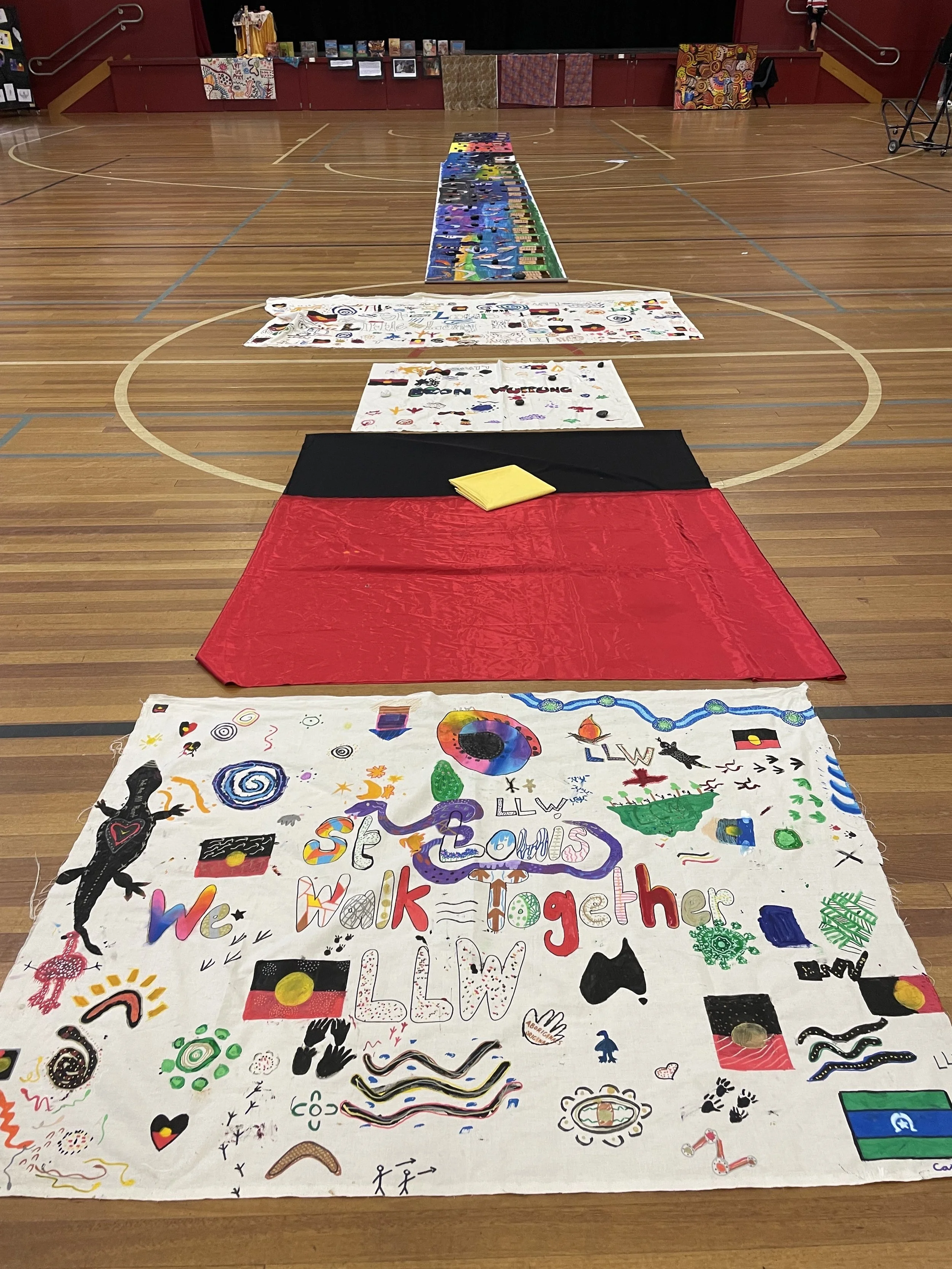 Colorfully decorated banner on a gymnasium floor with illustrations, symbols, and text celebrating togetherness and walking together.