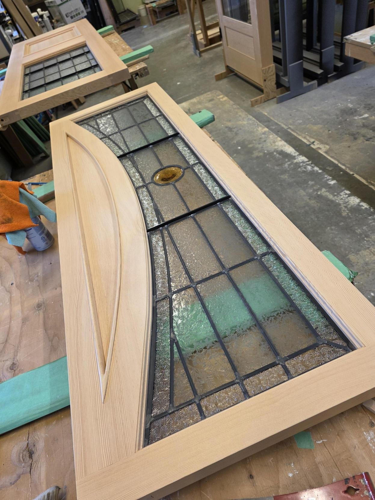 A stained glass door with a wooden frame and textured glass panels in a workshop.