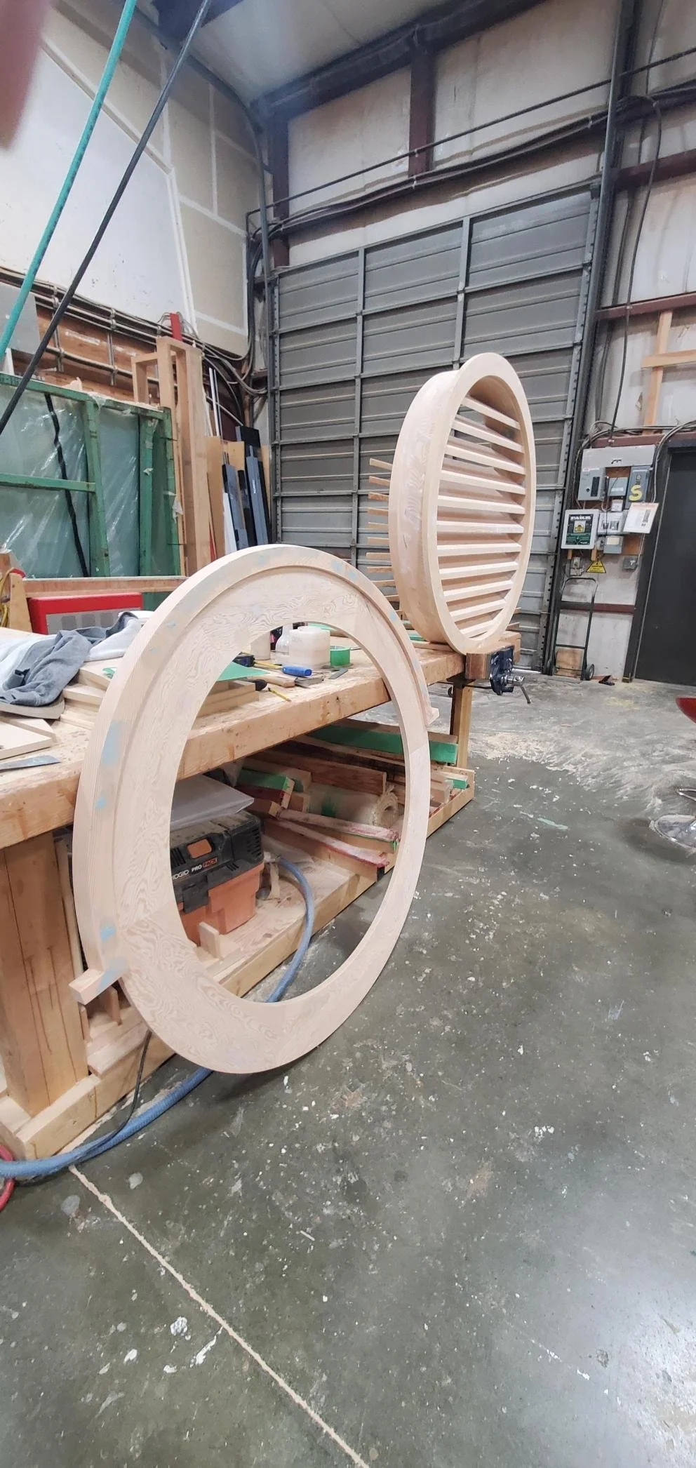 Two large wooden circular frames with slats in a woodworking shop, resting on a workbench.