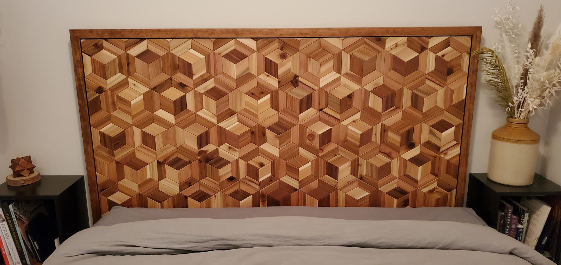 Wooden headboard with geometric cube pattern in a bedroom.