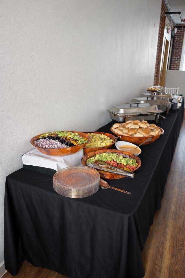 Buffet table with various salads, bread rolls, and serving trays in a dining area.