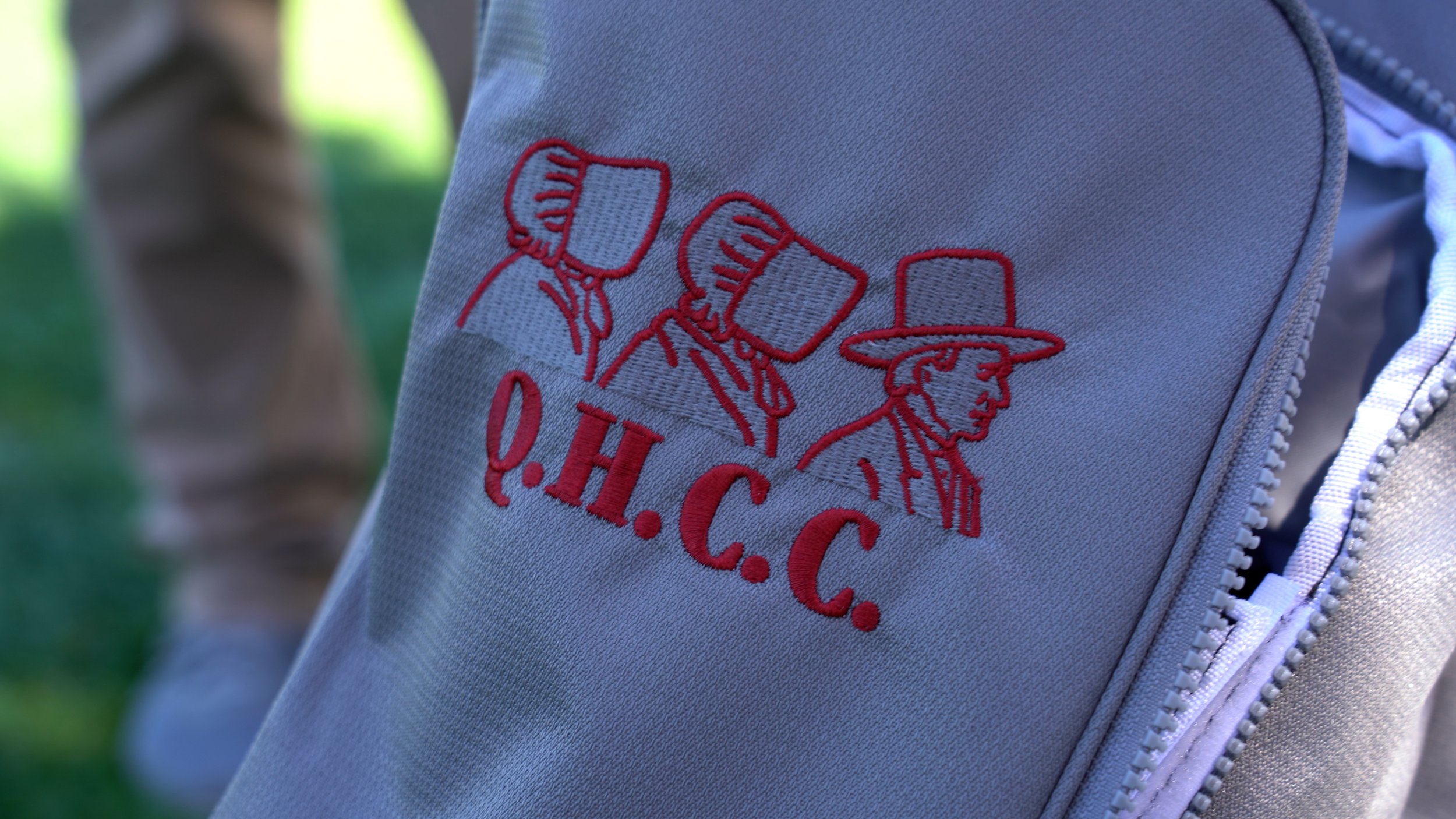 Close-up of a gray cloth item with red embroidery showing a police officer's head with a hat and the words 'O.H.C.C.'