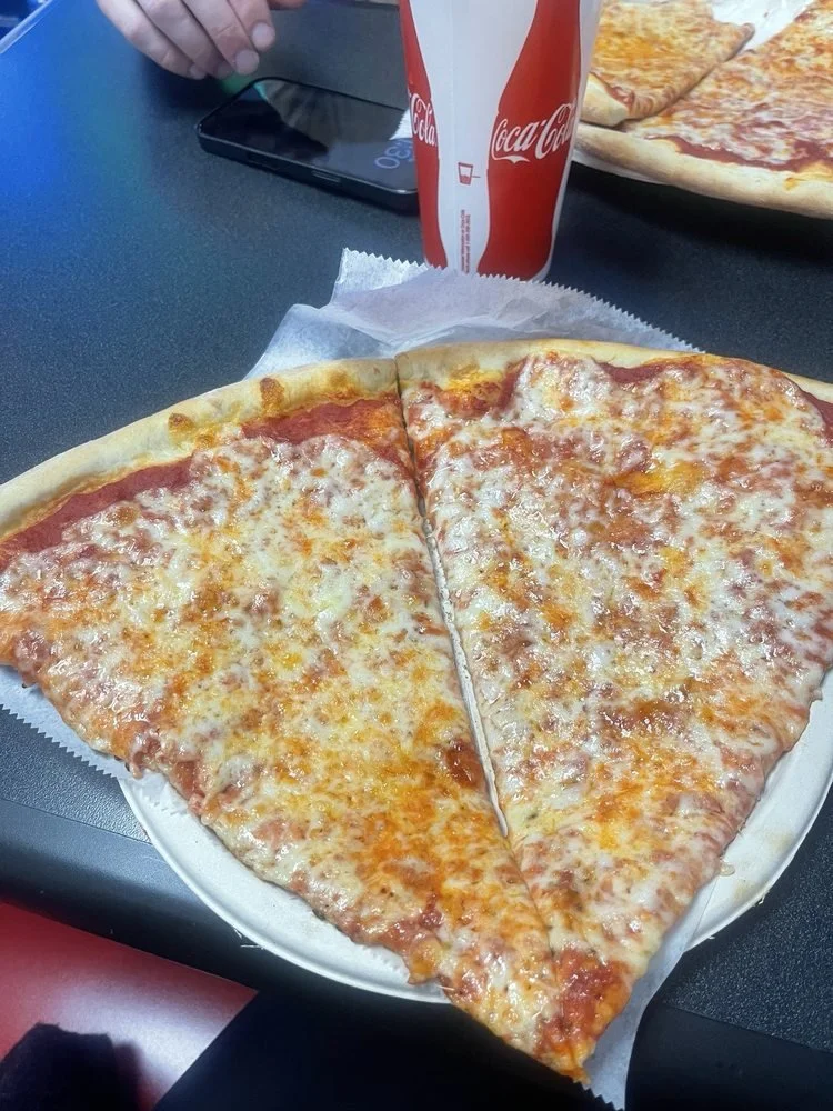 A plate with two large slices of cheese pizza and a cup of Coca-Cola in a restaurant setting.