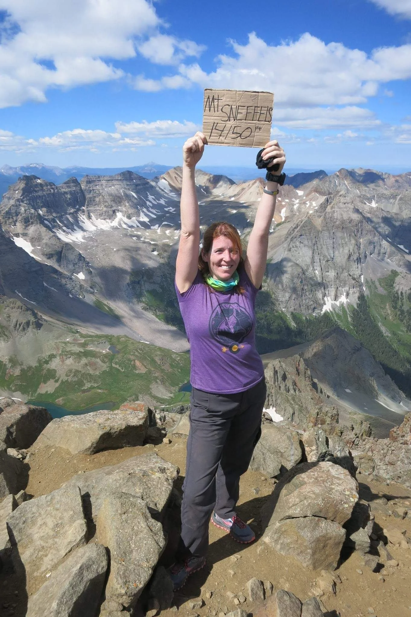 Jenn Overmeyer smiling on top of Mount Sneffels symbolizing the achievements reached through coaching and business consulting.