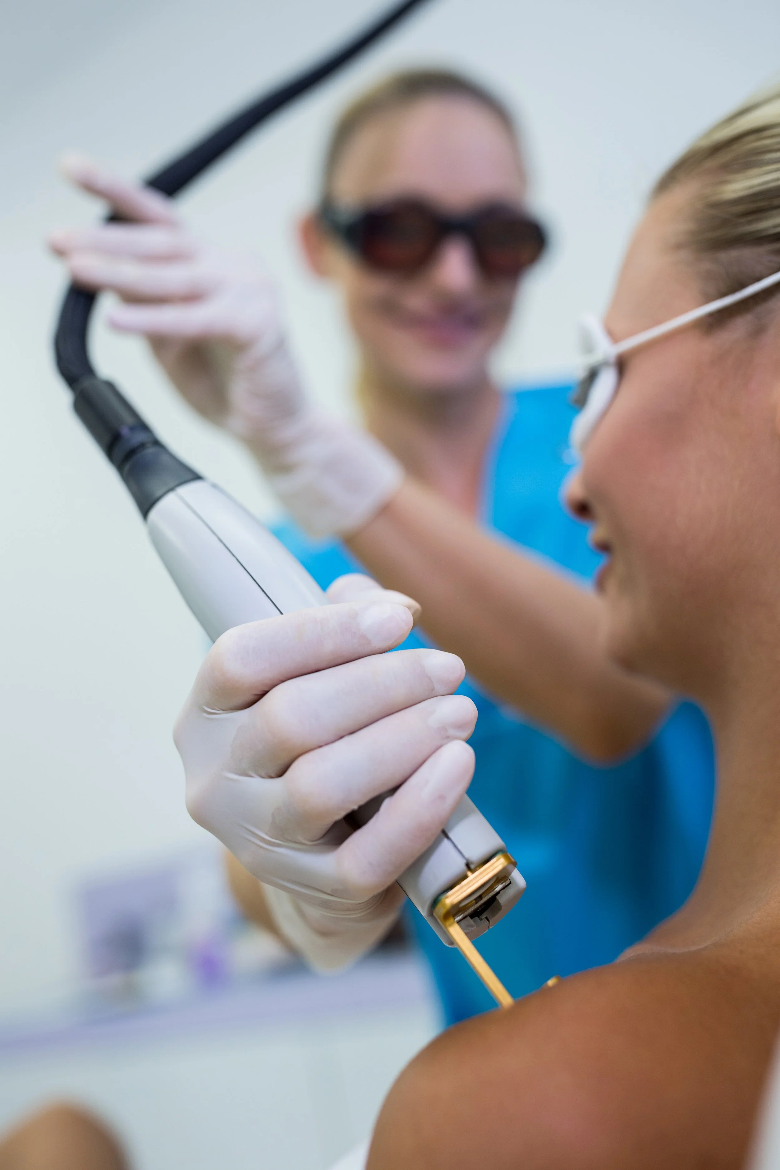 Close-up of a healthcare professional administering a medical procedure with a syringe to a patient’s arm, both wearing gloves and protective eyewear.