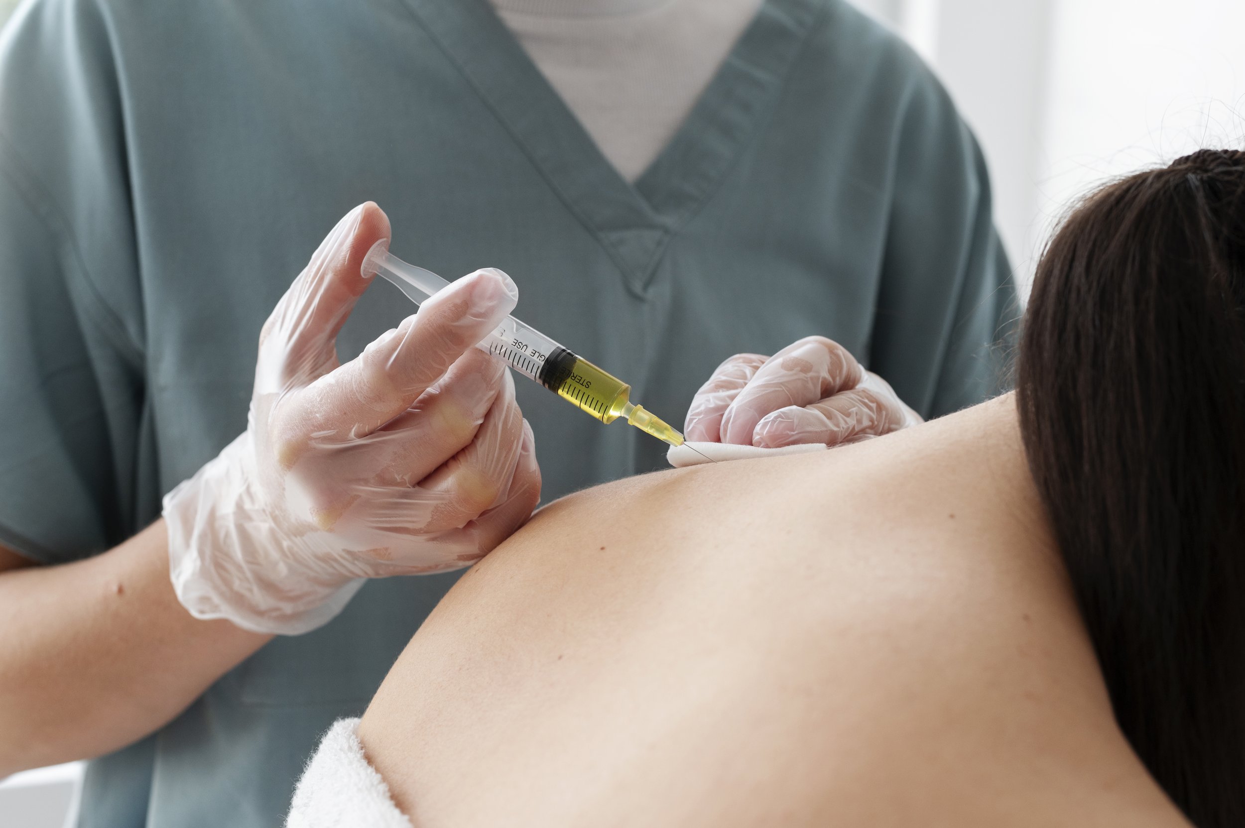 Medical professional administering a vaccination to a patient's upper arm using a syringe.