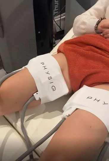 Person's arm with a blood pressure cuff labeled 'PHYSIO' attached during a medical exam.