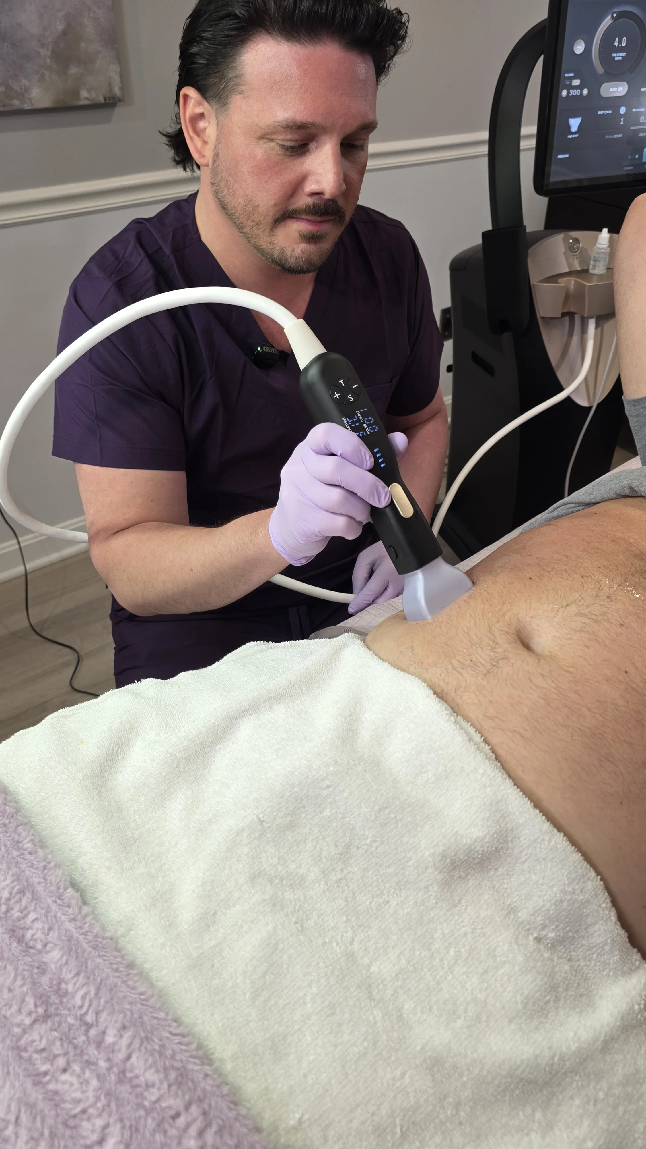 Healthcare professional performing a medical procedure on a patient's abdomen using a handheld ultrasound device.