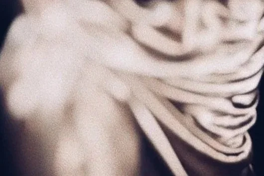Close-up of a person wearing a striped shirt, pulling the shirt away from their shoulder.