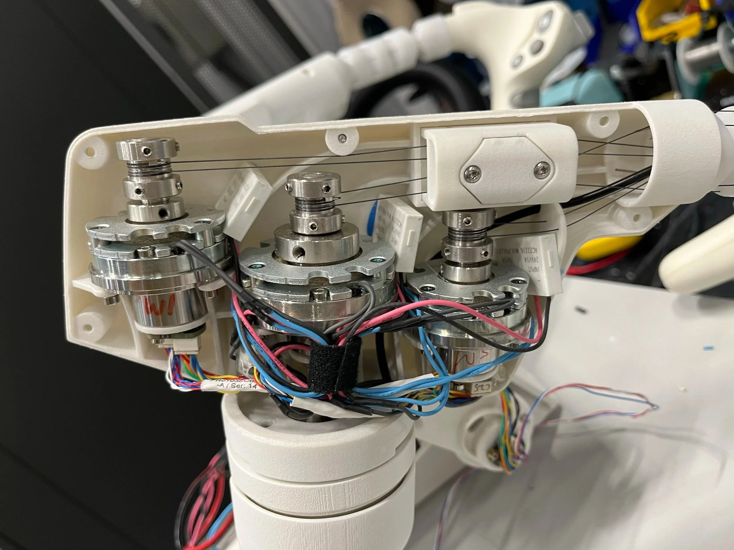 Close-up of the internal components of a robotic device with wires, gears, and metal parts assembled inside a white plastic casing.