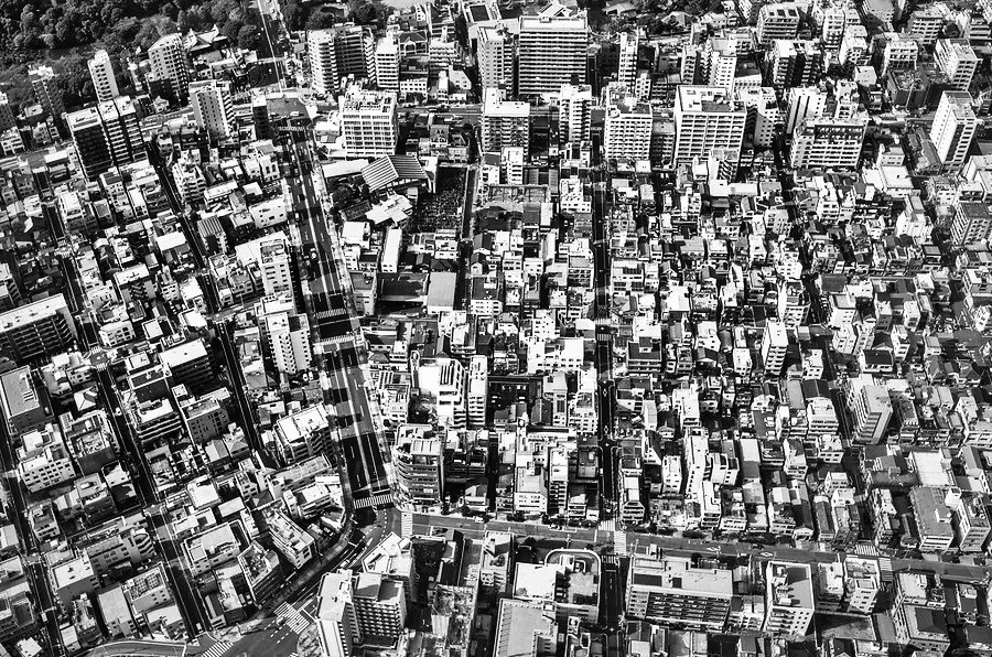 Aerial view of a dense cityscape with numerous high-rise buildings and a network of roads in black and white.