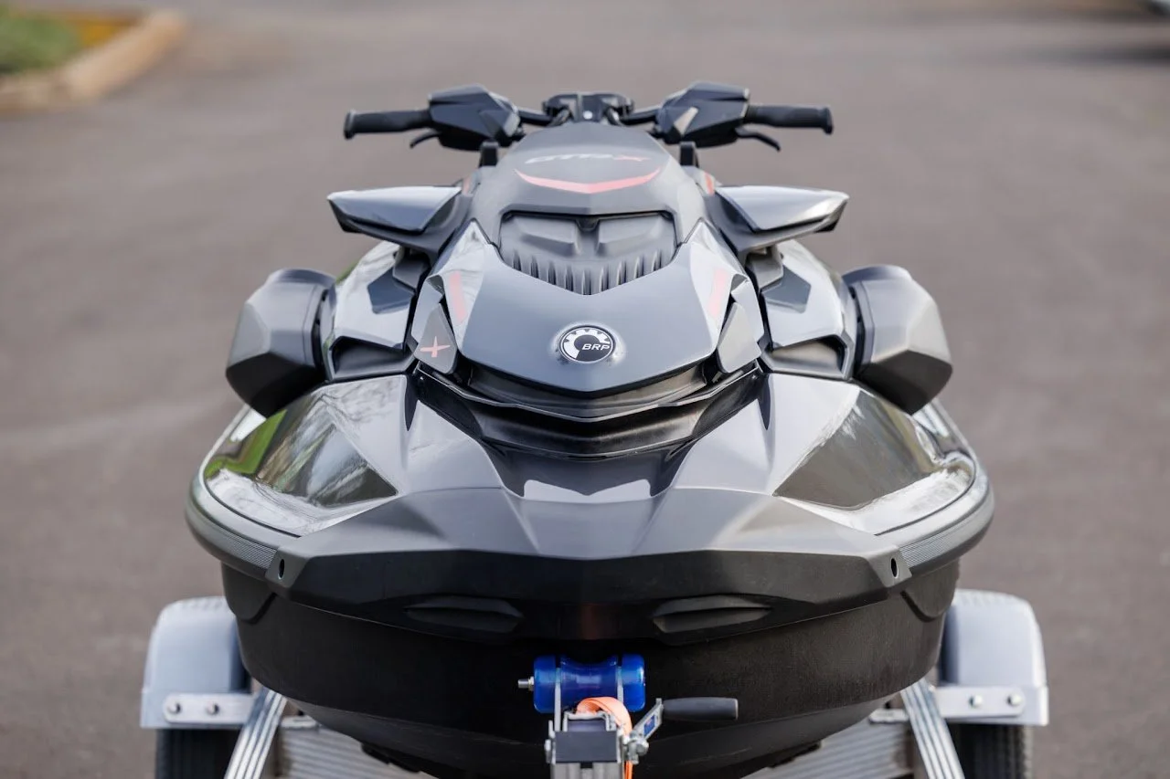 Front view of a sleek, black and gray jet ski on a trailer, with handlebars and a glossy surface.