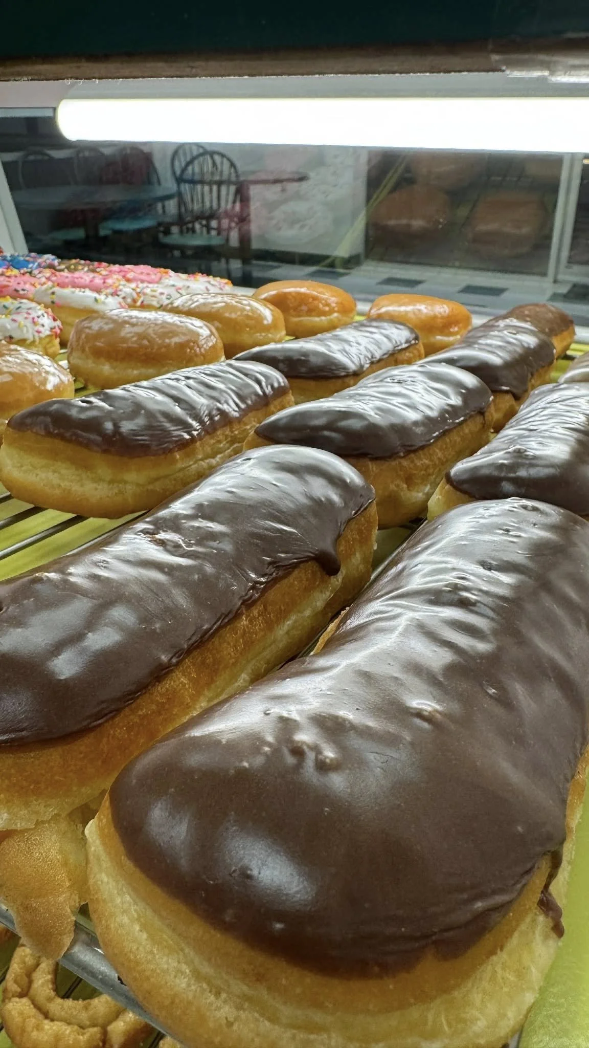 Display of chocolate-glazed eclairs at a bakery.
