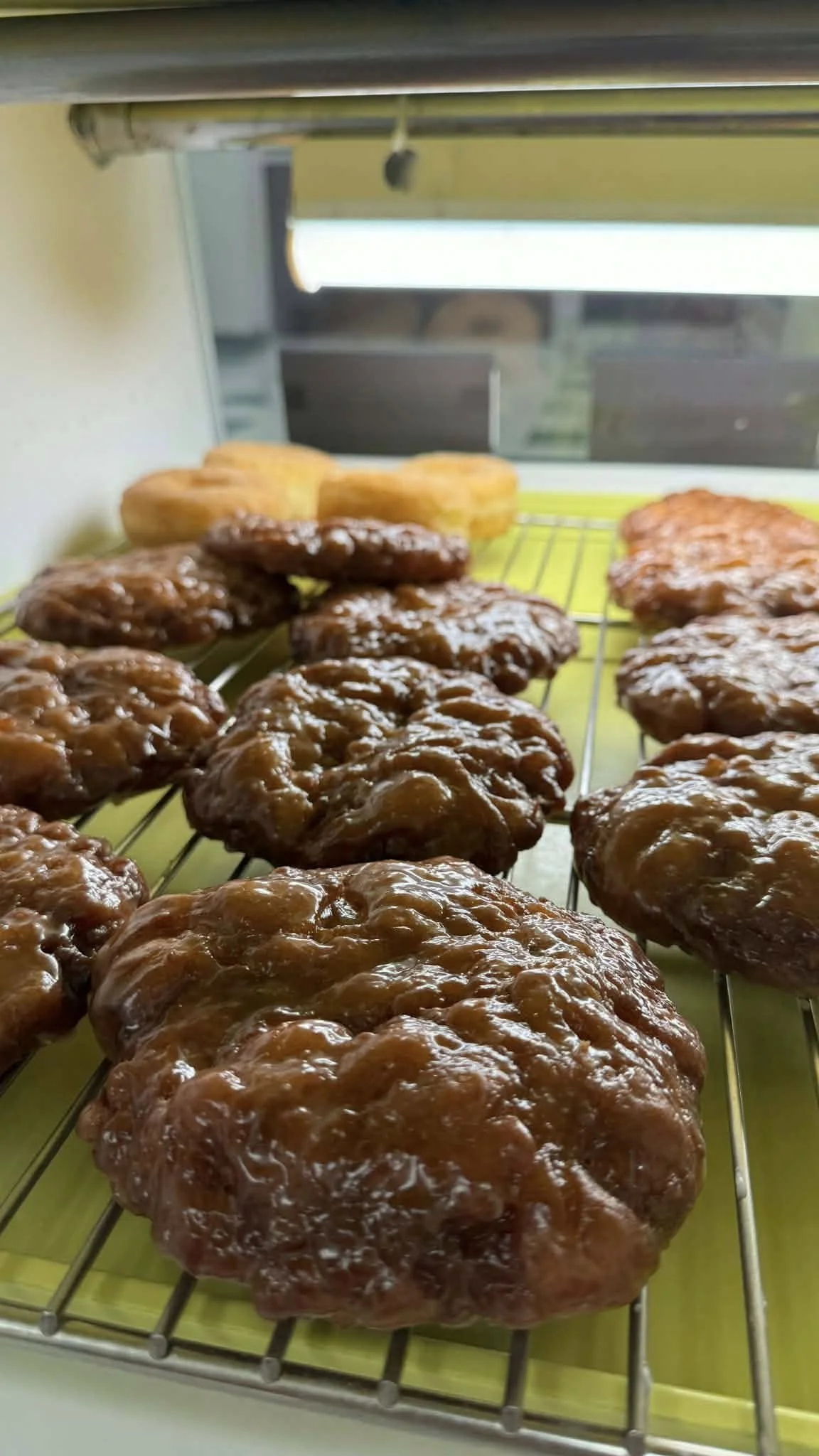 Close-up view of cooked glazed meat patties cooling on a wire rack with some baked goods in the background.