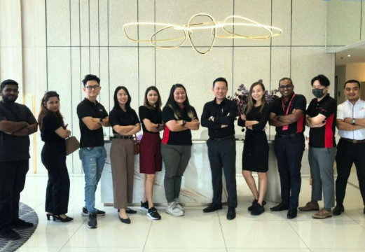 MoU of Sleepy Bear Group. Group of ten diverse people standing in a modern office lobby in front of a reception desk, posing for a photo.