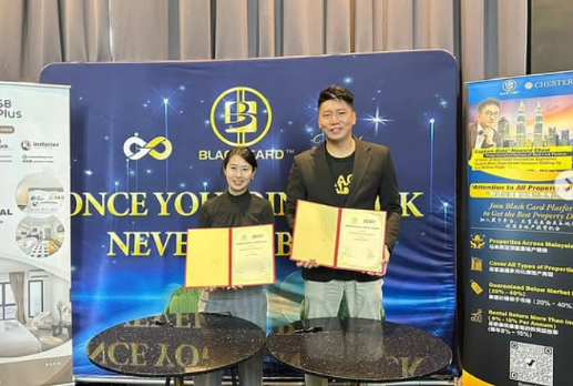 MoU of Sleepy Bear Group. Two individuals standing in front of a blue backdrop with gold and white logos, holding certificates, in a formal event setting.