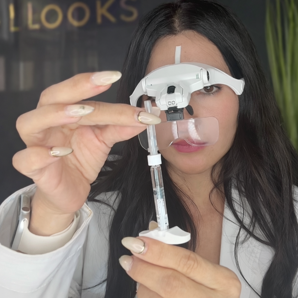 A woman with dark hair looking through specialized medical eyewear, holding a syringe in one hand and adjusting the device with the other.