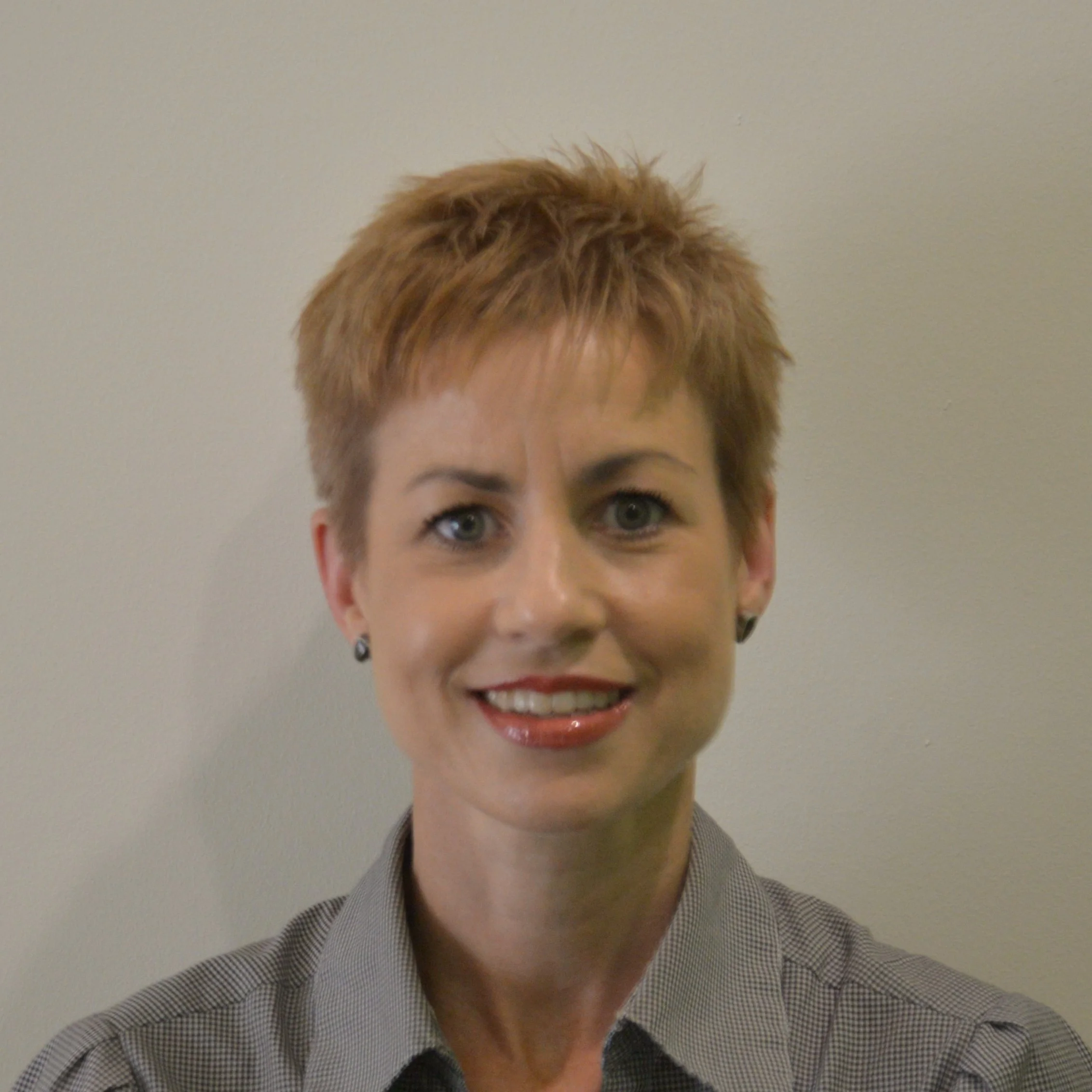 A woman with short hair smiling in front of a background with the text 'HIT sa' and 'Training and Employment RTO Code 40200'.