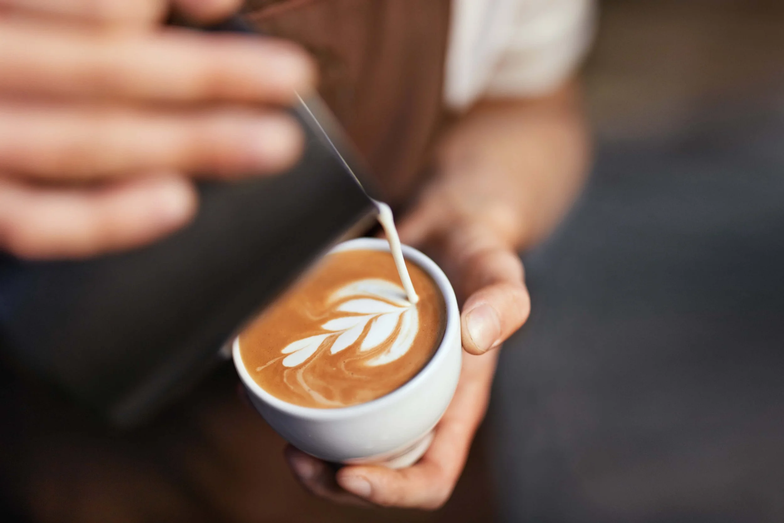 Close-up of a barista creating latte art in a cup of coffee.