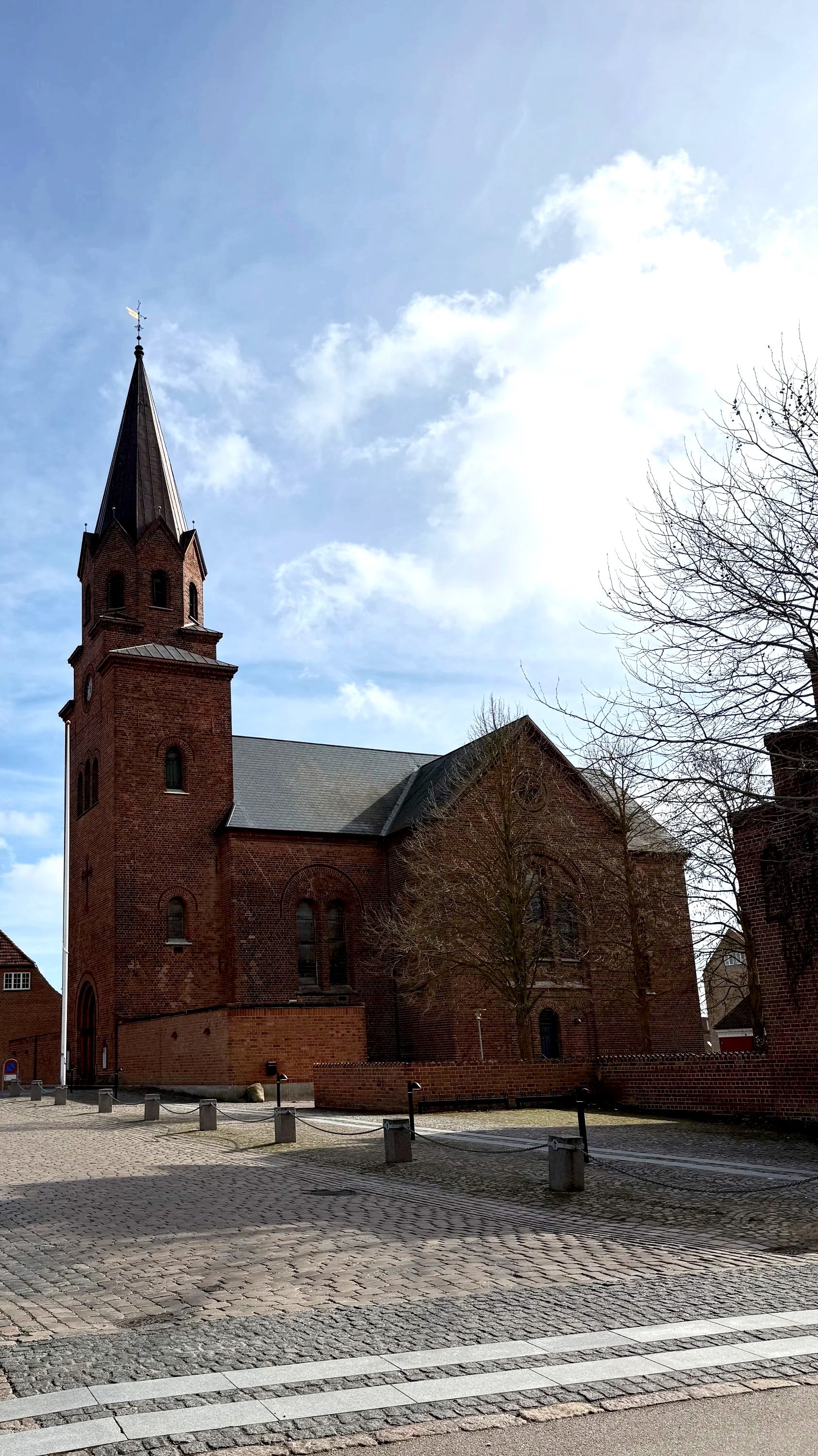 Kirkestræde i Holbæk, den nærtliggende kirke under en høj blå himmel.