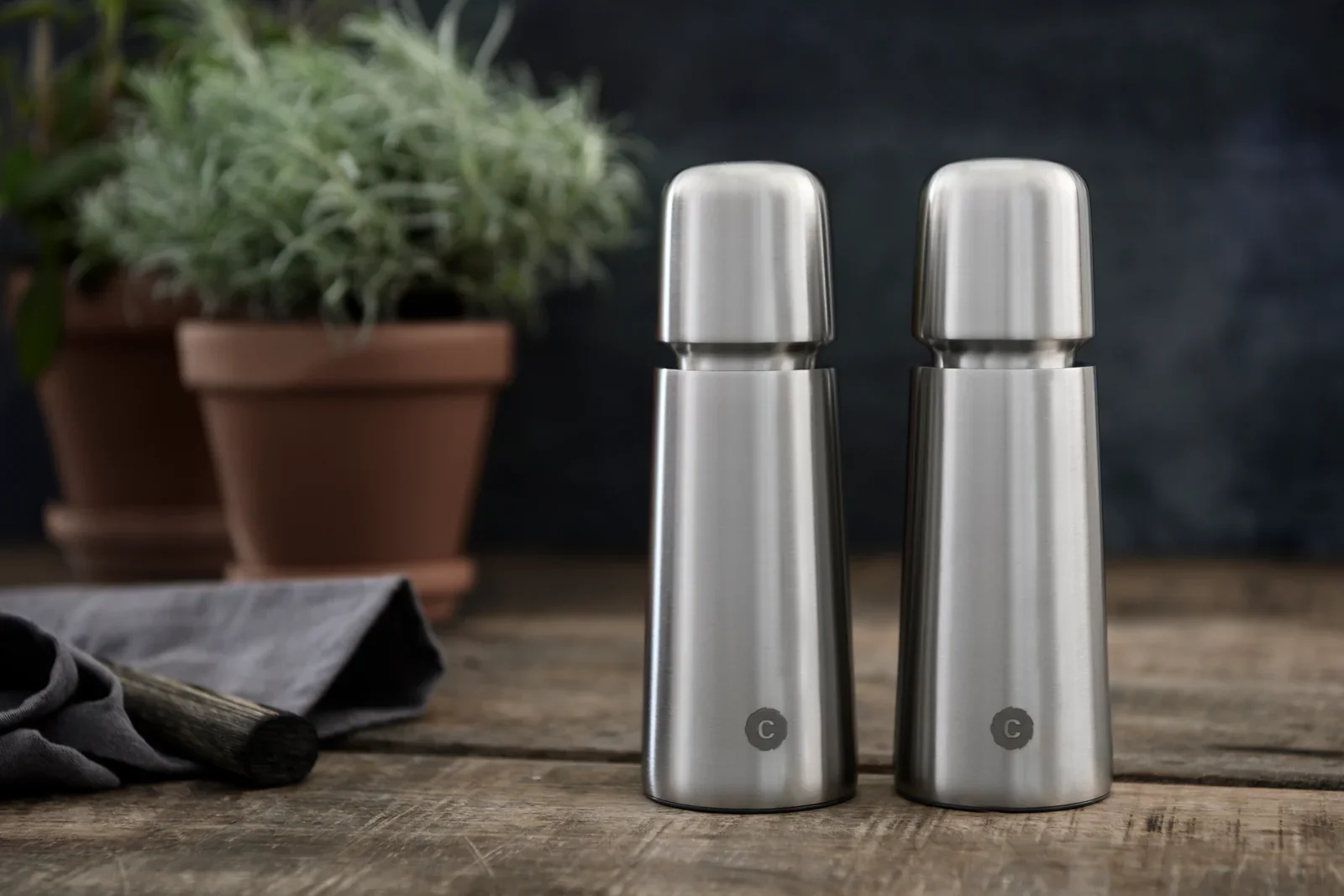 Stainless steel salt and pepper shakers on a rustic wooden table.