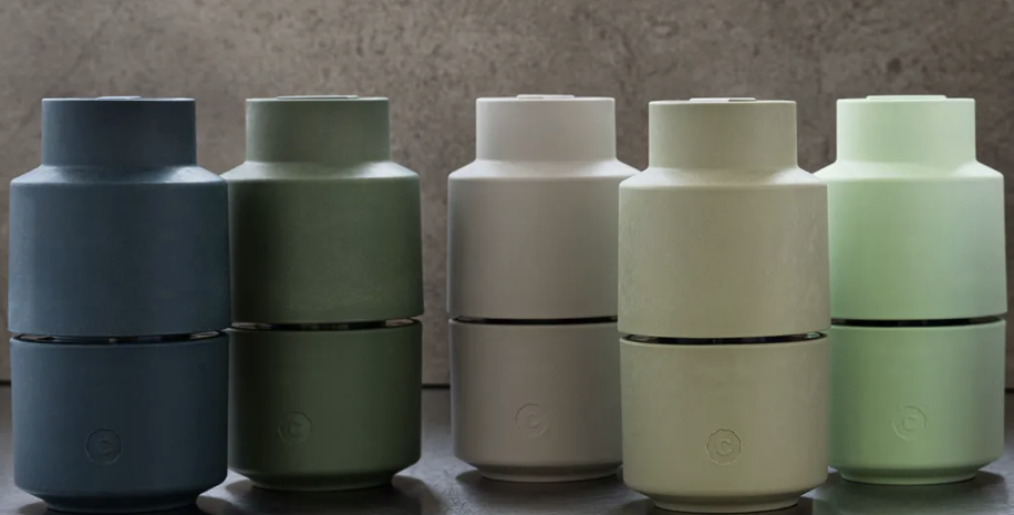 Five sets of color-tinted, two-piece ceramic containers or jars, arranged in a row against a neutral background, each set including a larger and smaller piece.