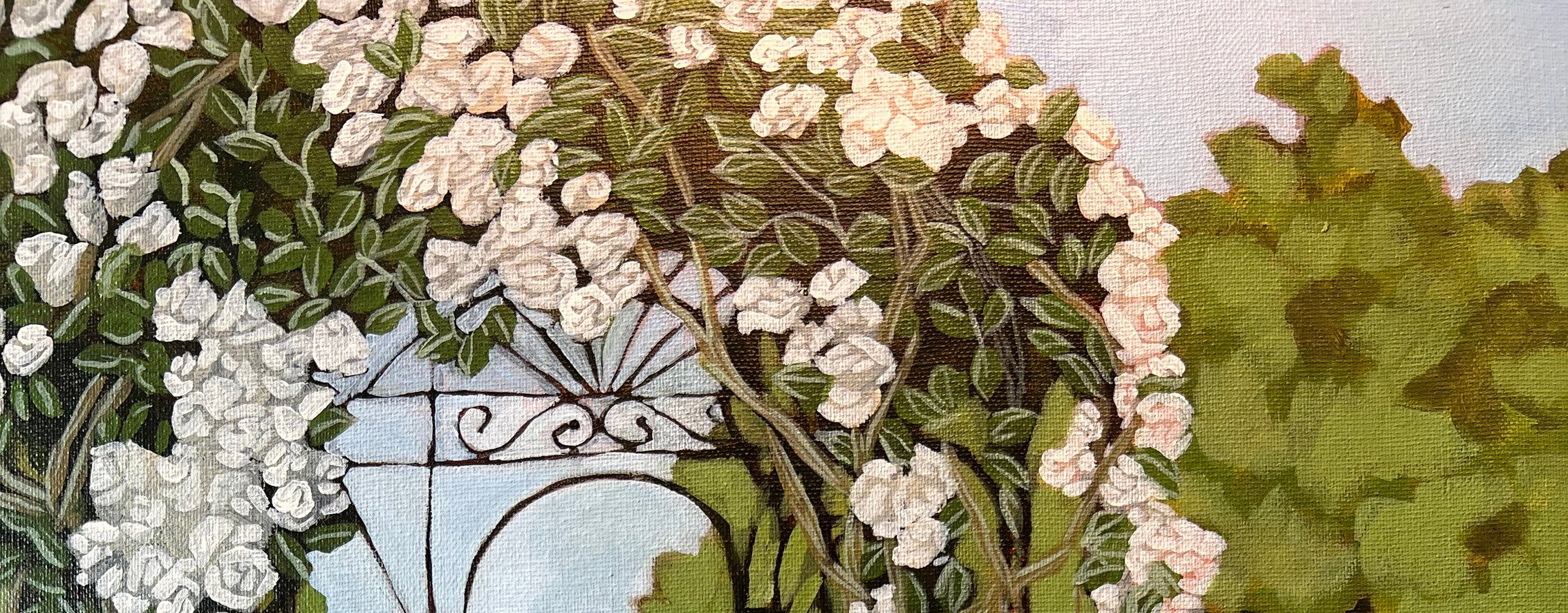 Close-up of a garden ornament, a white metal vase with black decorative swirls, surrounded by white and pink flowers and green foliage.
