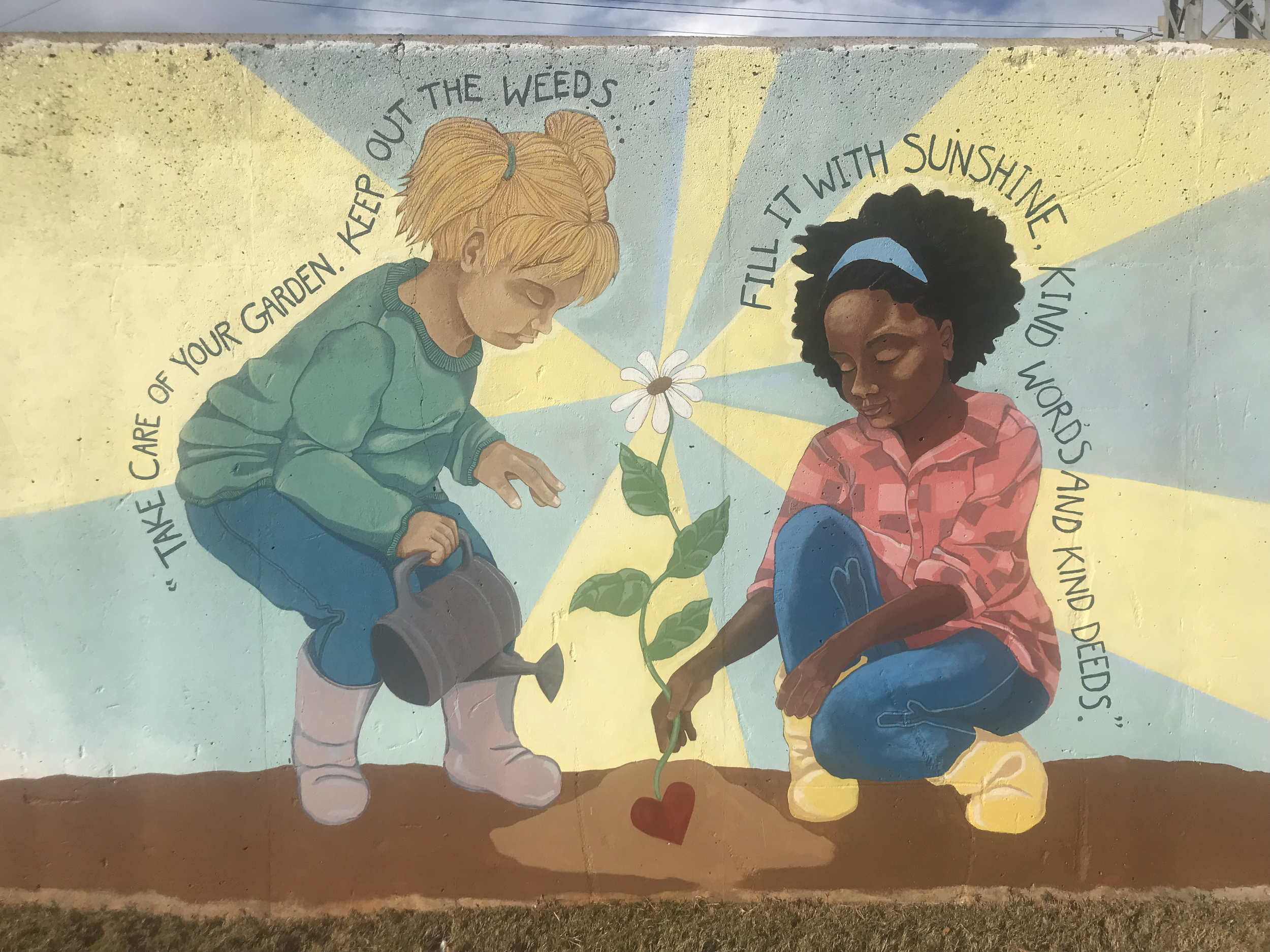 Colorful mural of two children planting a flower together, with a quote about caring for the garden and filling it with sunshine.