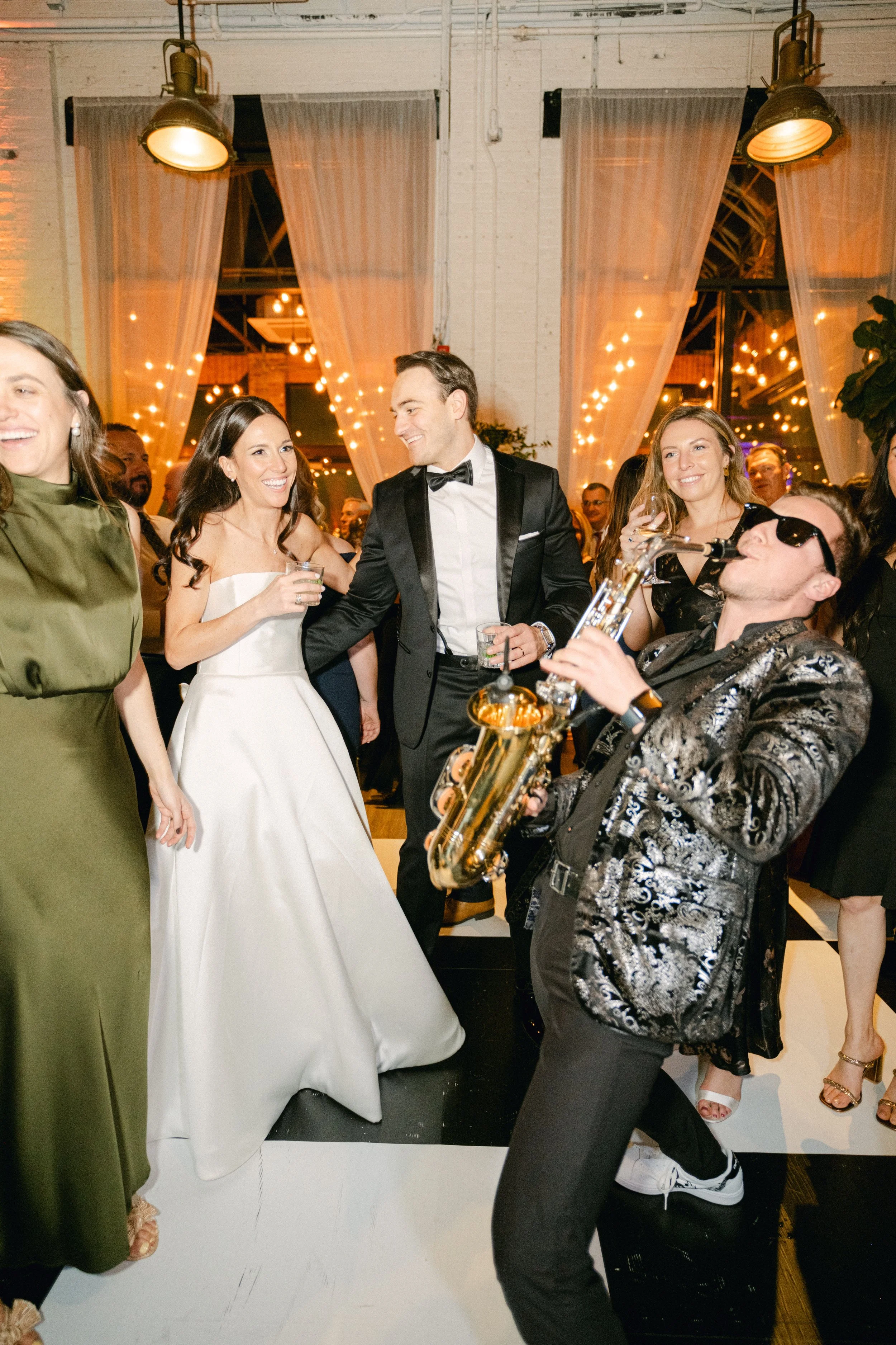Guests dancing and celebrating at a Miami wedding reception in a decorated venue with a live, high-energy saxophonist.