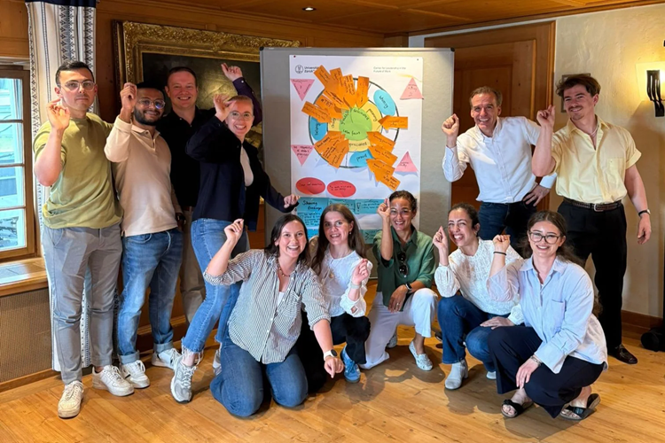 Group of workshop participants posing together as though throwing darts, standing around a colorful Emotional Fit Dartboard