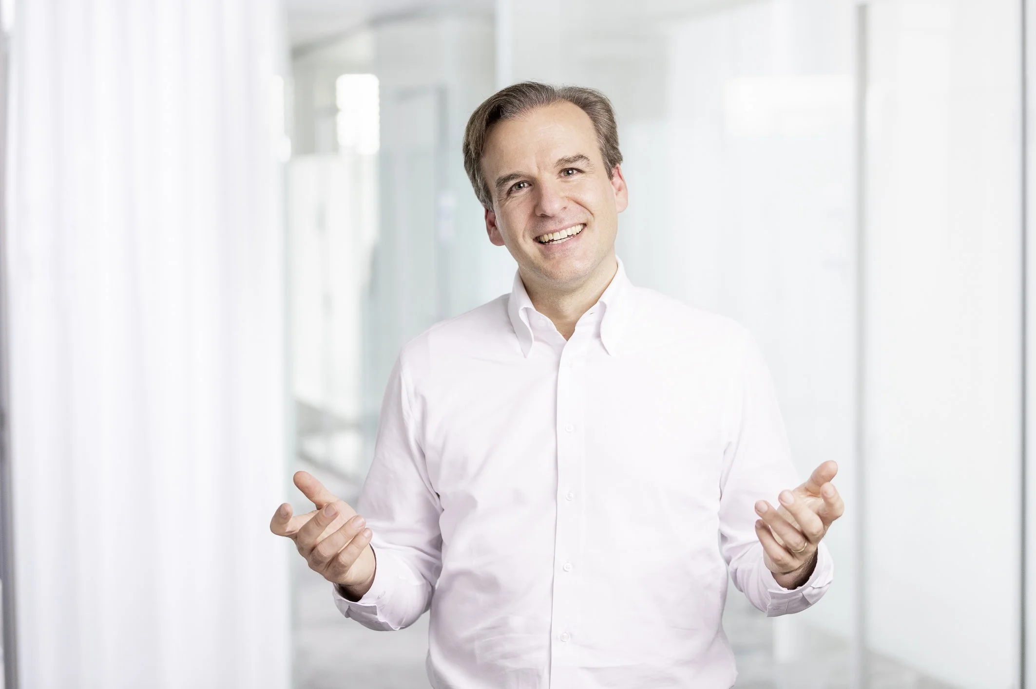 Jochen Menges speaking with open hands against a bright office background.