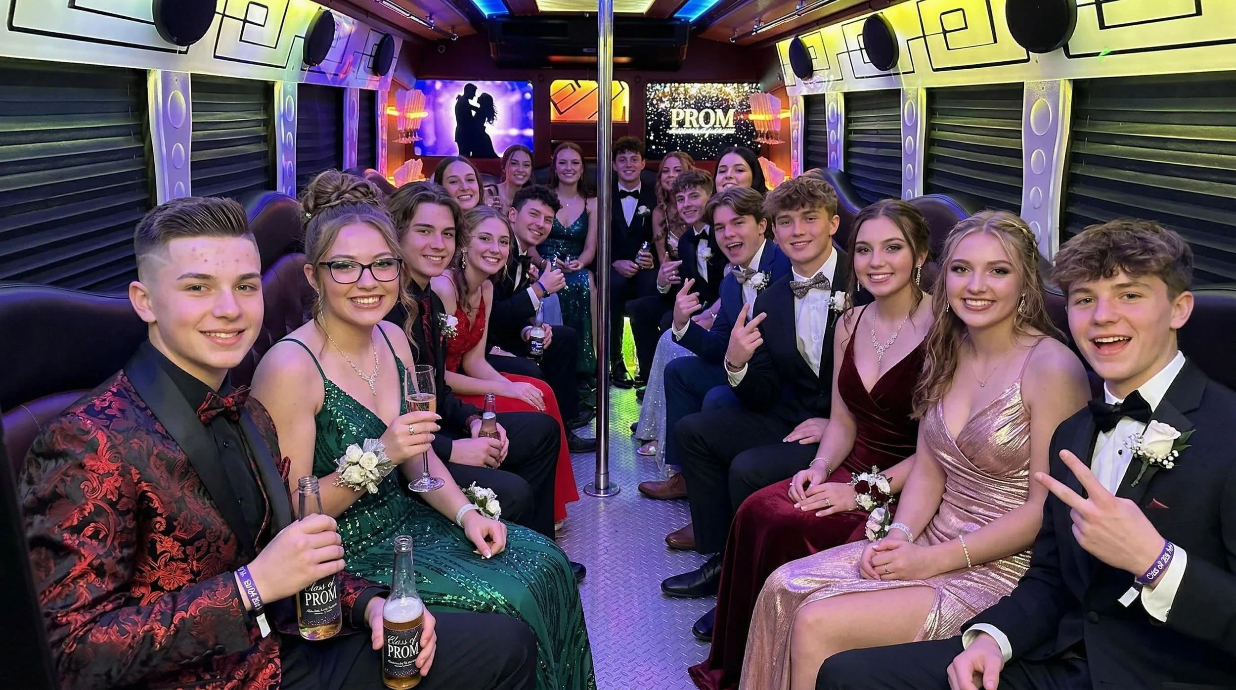 Group of teenagers dressed in formal attire inside a party bus, celebrating prom night with drinks and happy expressions, with a 'PROM' sign on a screen in the background.