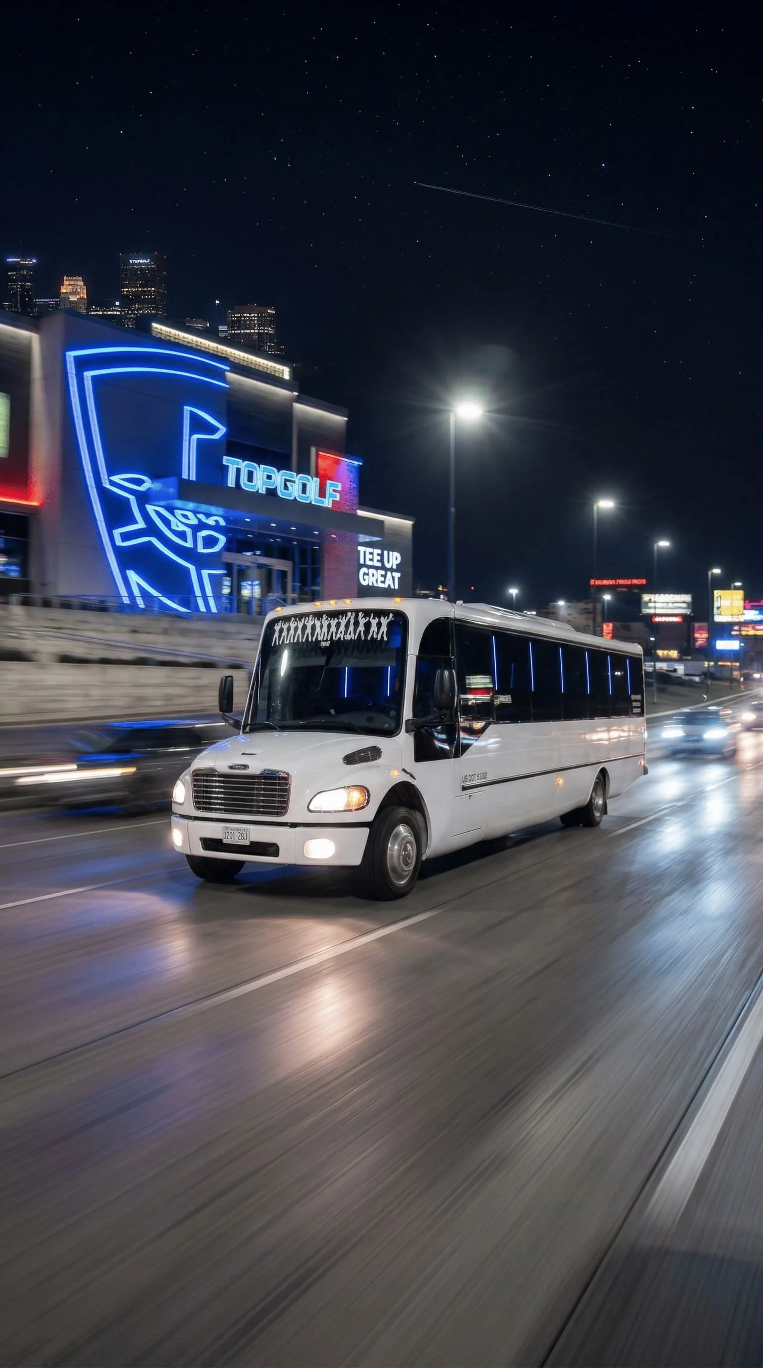 A white shuttle bus driving on a highway at night with city buildings and neon lights in the background.