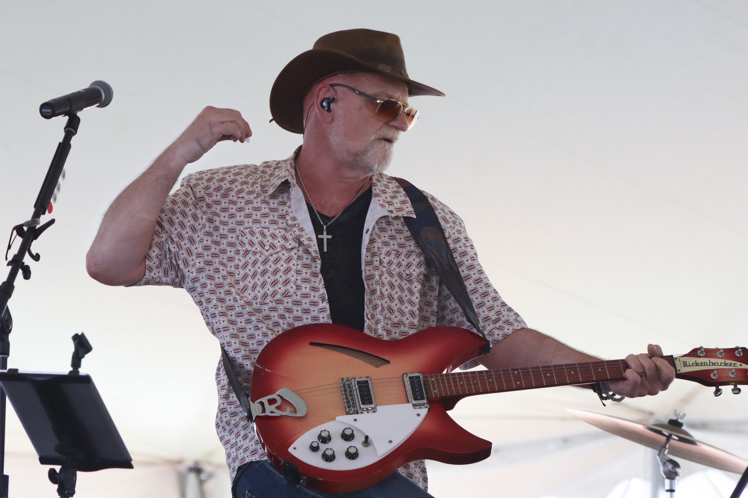 Man in a cowboy hat strumming an electric guitar onstage