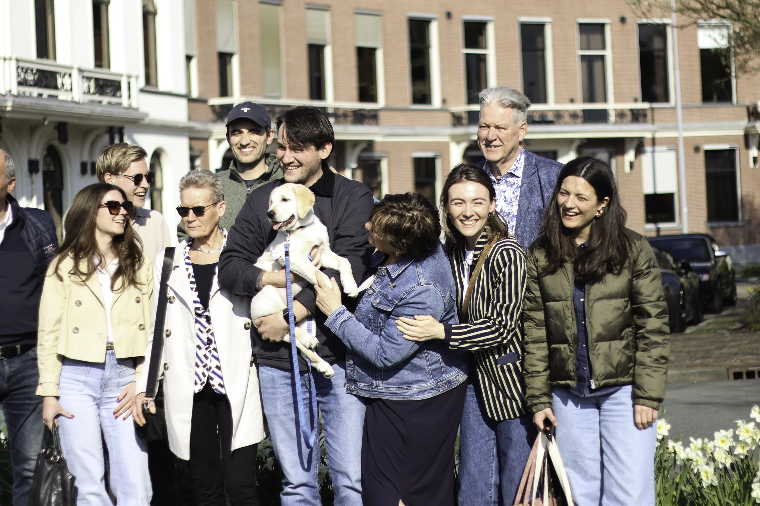 Multigenerational family with dog, standing while smiling, posing for a portrait