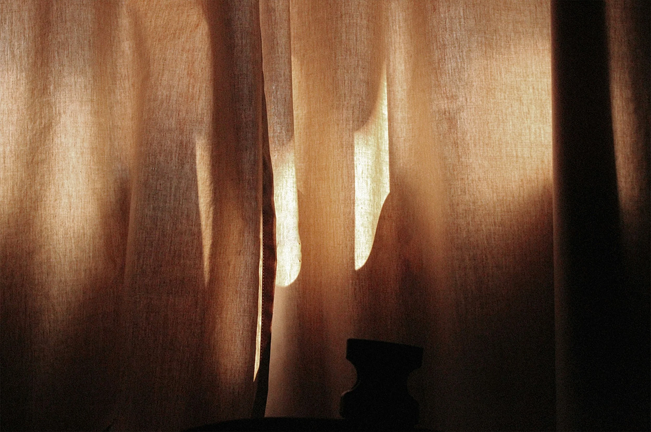 Close-up of brown fabric curtains with sunlight filtering through.