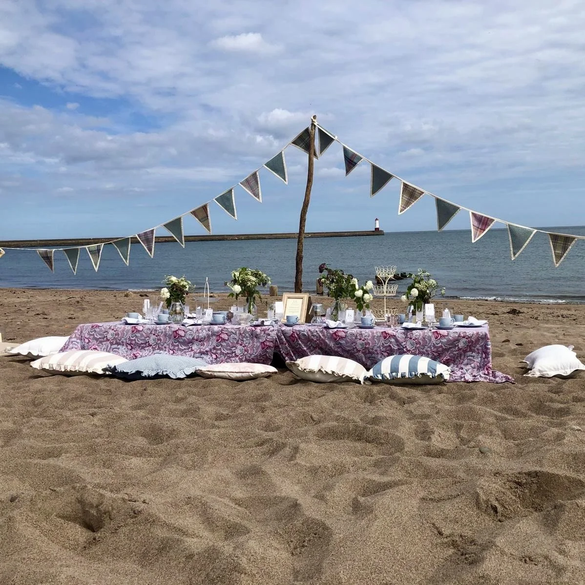 Luxury milestone birthday picnic on Spittal Beach in Berwick-upon-Tweed, Northumberland, styled by Laura Somborn with vintage tableware, elegant decor and coastal views.