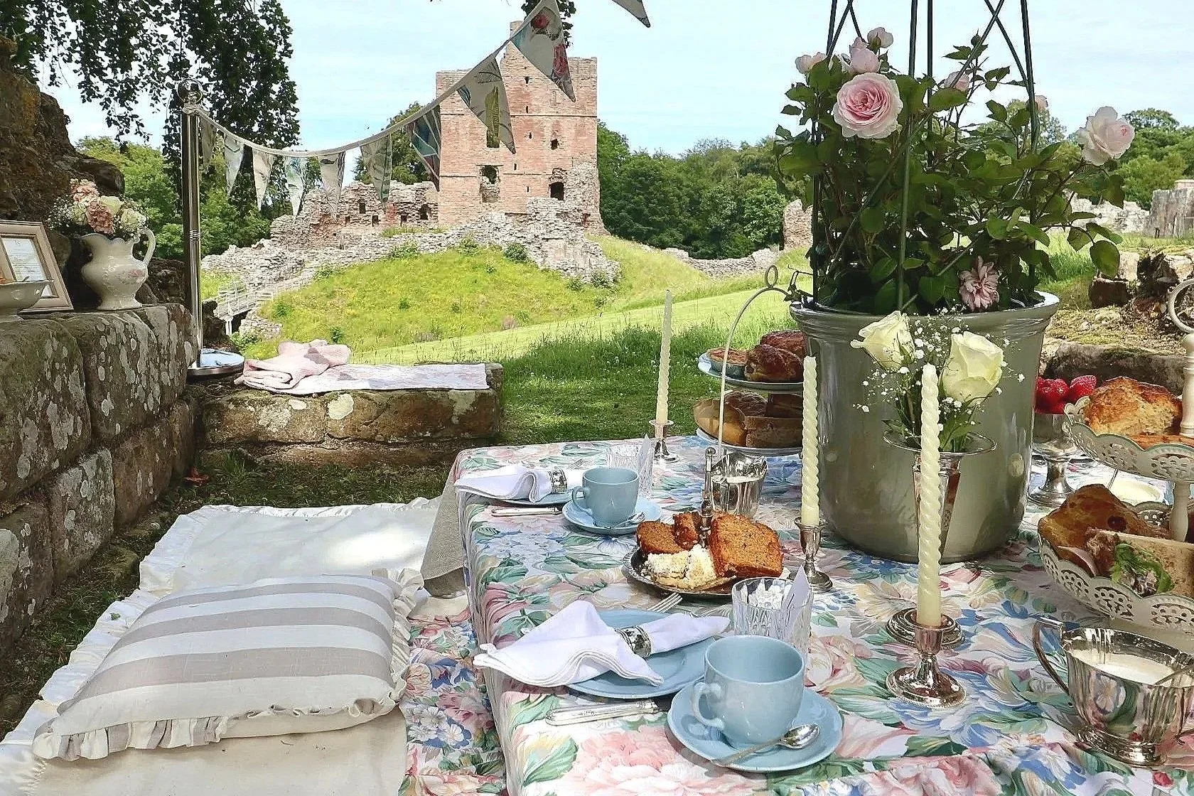 Bespoke castle garden tablescape by Laura Somborn featuring seasonal flowers, heritage tableware and the historic ruins of Norham Castle, Northumberland.