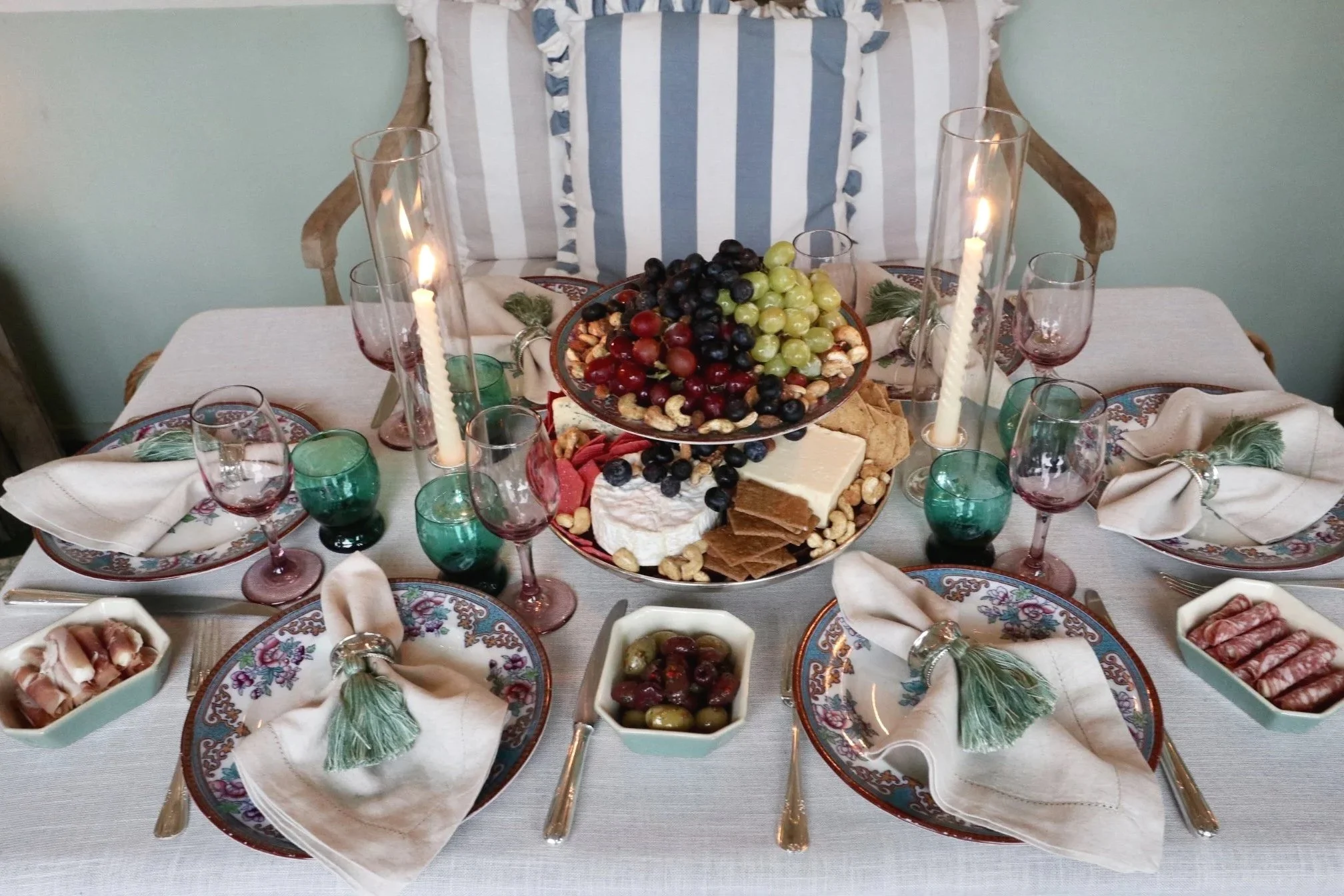 Grazing platter of grapes, cheeses, nuts and crackers arranged among heritage tableware and candlelight.