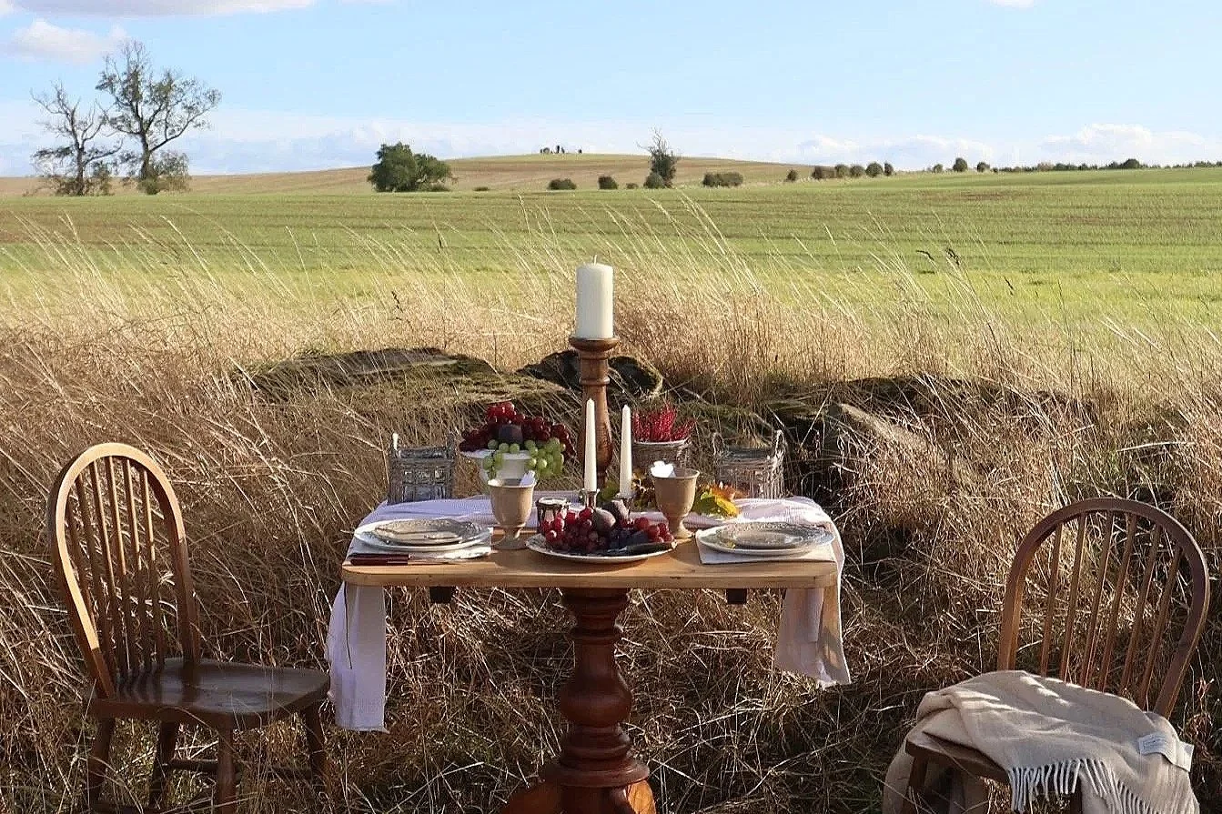 Rustic autumn tablescape with earthenware goblets, candles, grapes and berries, set in an open Northumberland landscape.